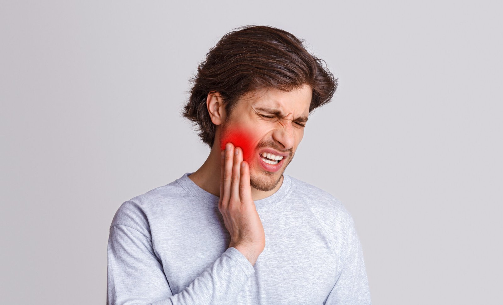 A person holding their jaw in discomfort, illustrating the immediate need for Emergency Dental Care in Beverly Hills.